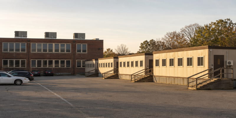 A public school campus showing rooftop units on the main building and mini-split condensers on portable classrooms